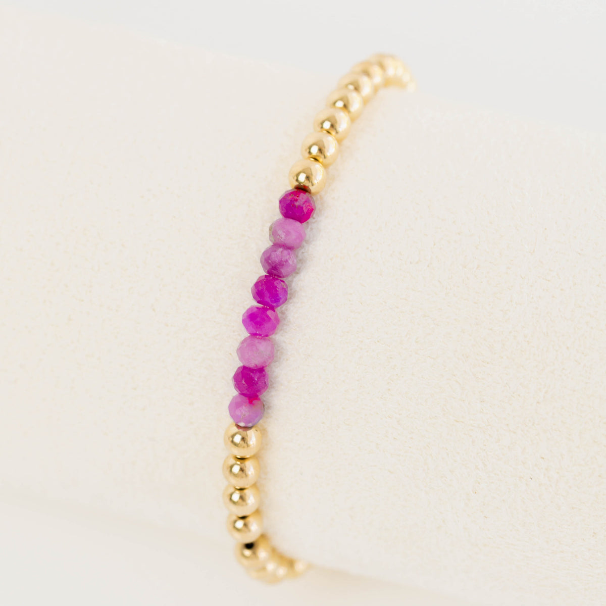 Bracelet with gold and pink beads on a beige background
