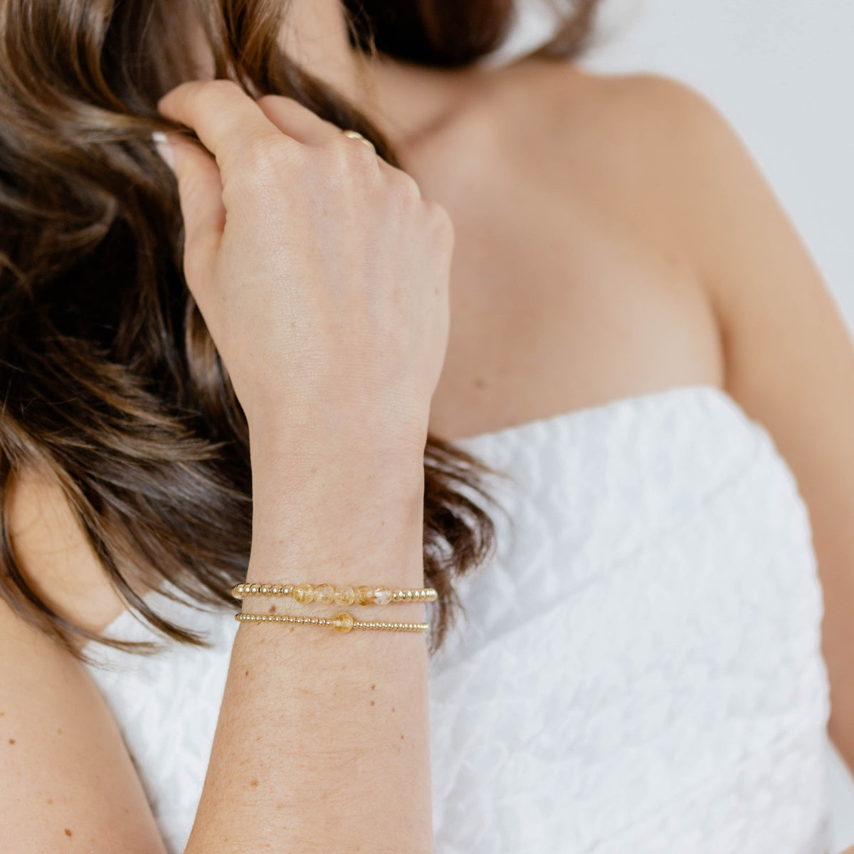 Person wearing a gold bracelet with a blurred background
