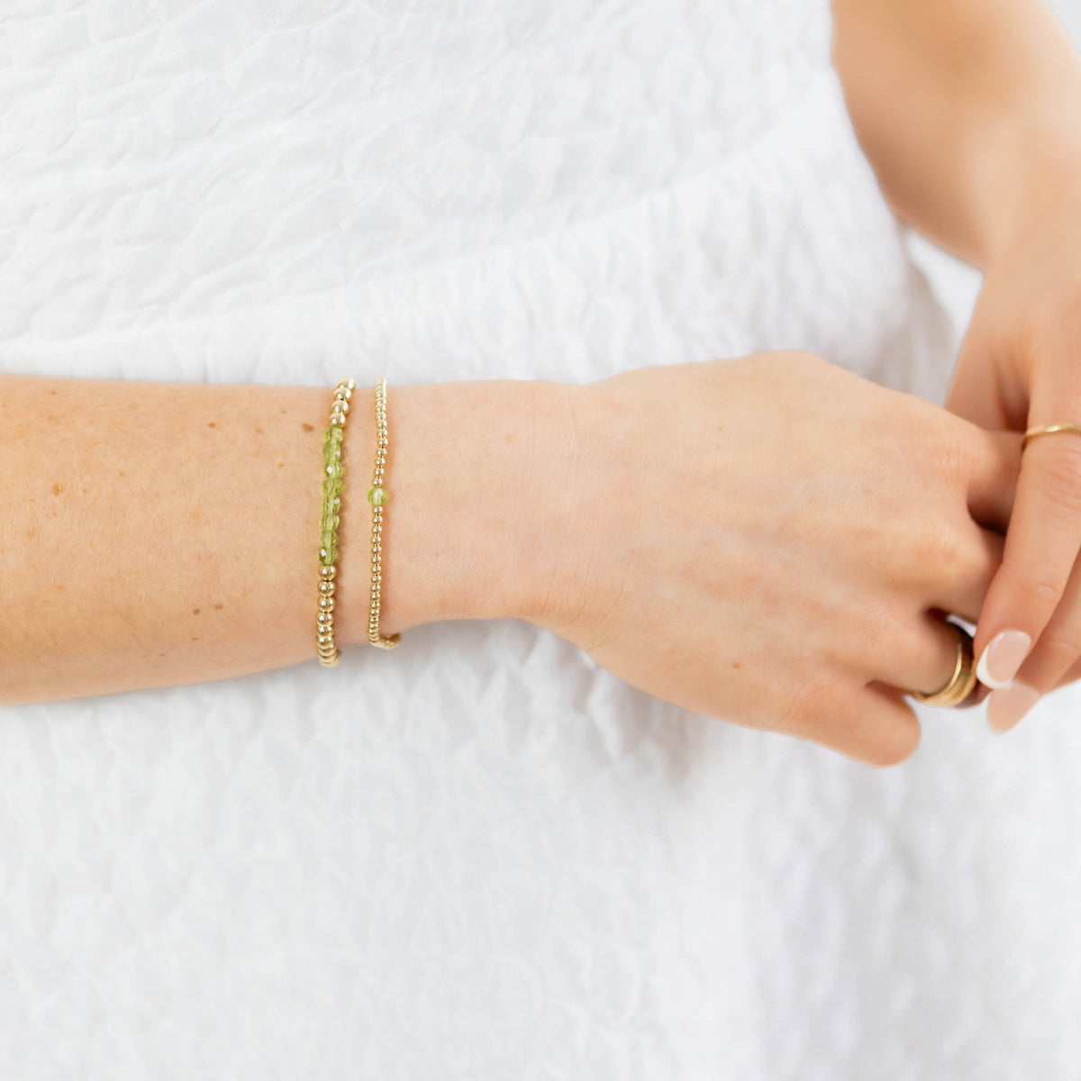 Close-up of a person's wrist with two bracelets on a white background